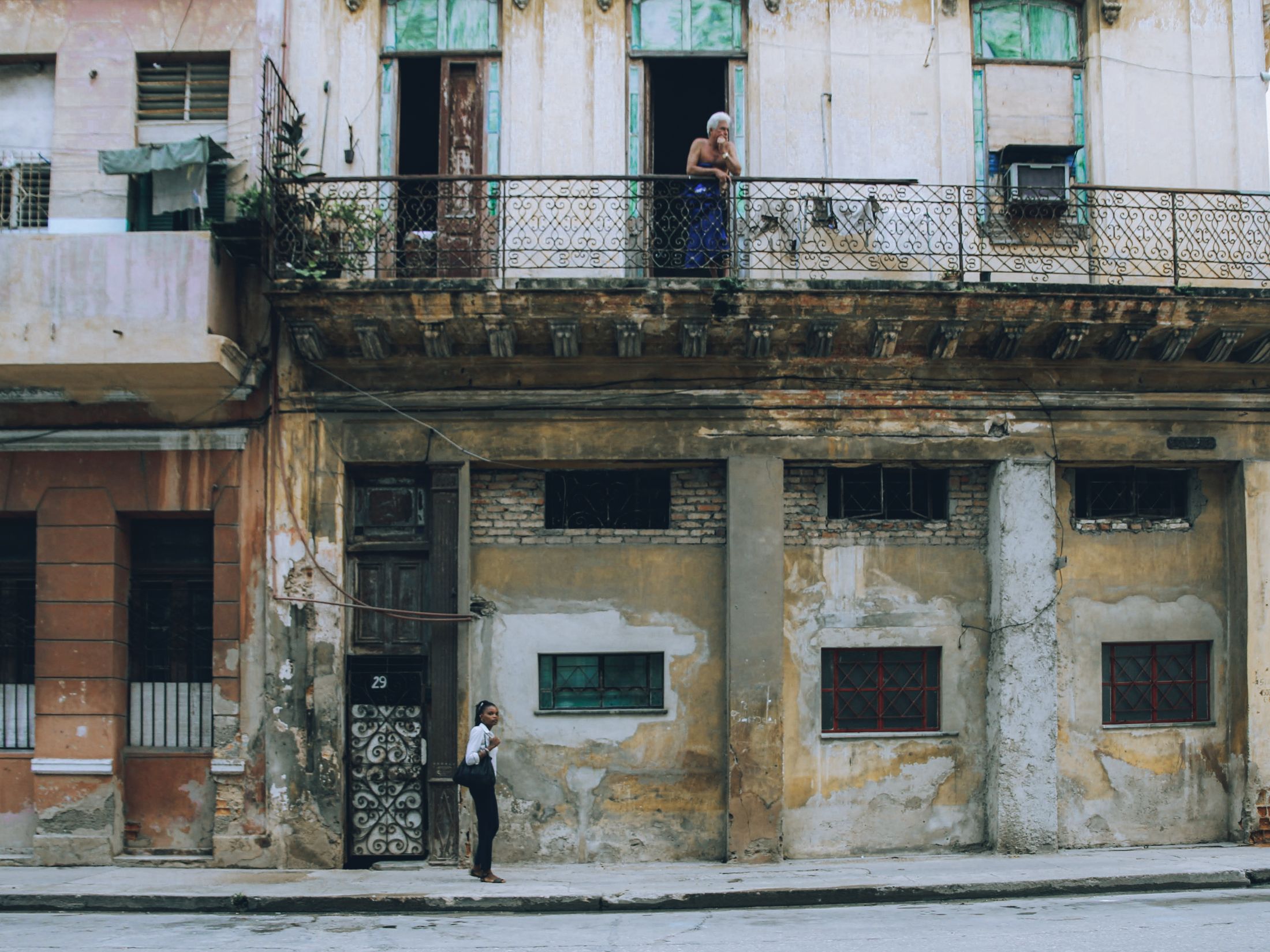 Edificio deteriorado con un vecino en el balcón, Cuba